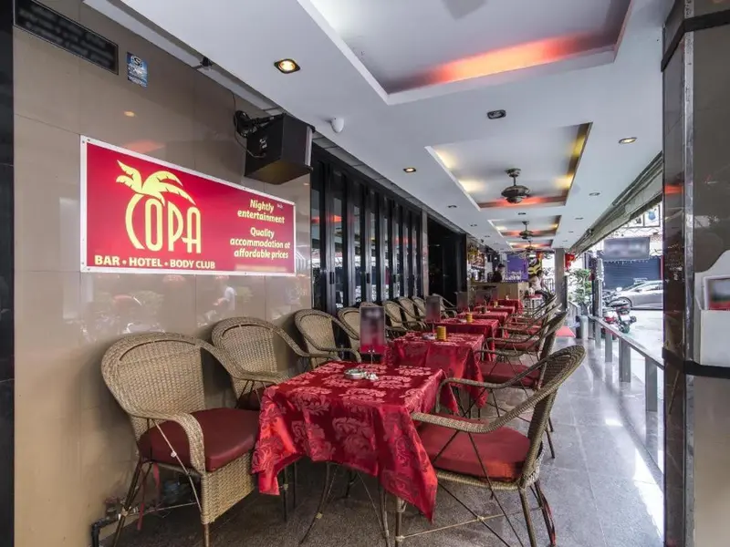 Terrasse de restaurant avec tables et chaises sous un auvent rouge.