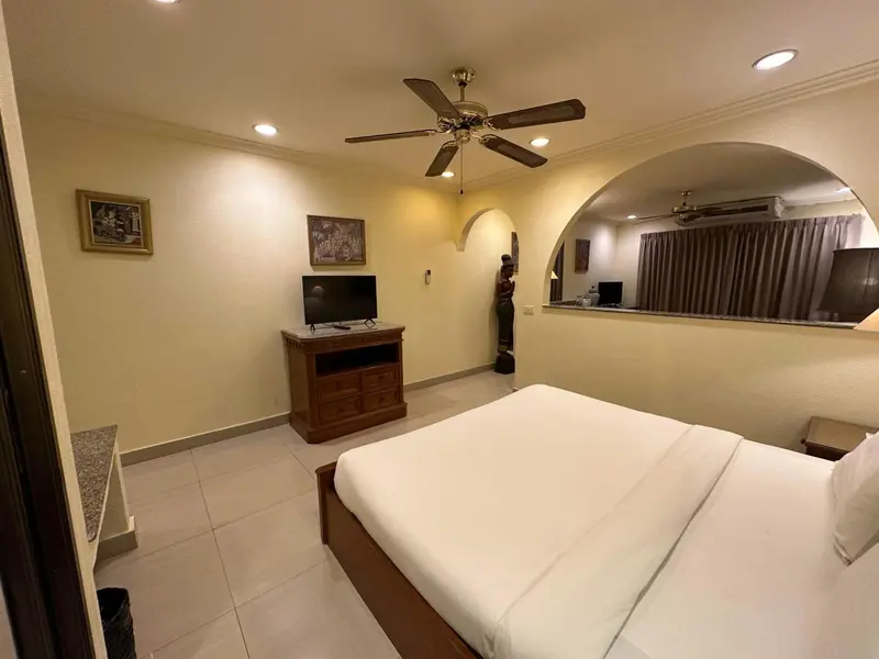 Une chambre lumineuse avec un grand lit et un téléviseur.