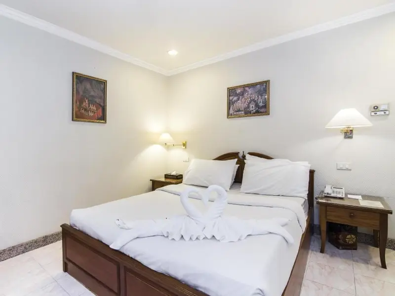 Une chambre lumineuse avec un grand lit recouvert de draps blancs et décoré de serviettes en forme de cygne.