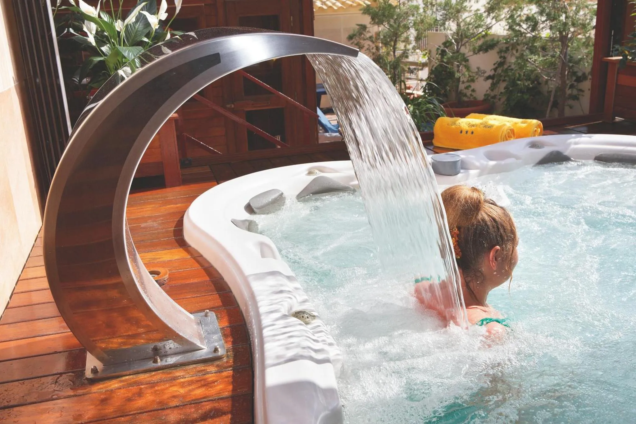 Une personne se détend dans un jacuzzi extérieur avec une cascade d'eau.