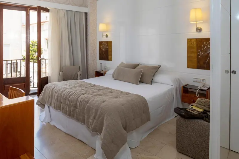 Une chambre lumineuse avec un grand lit et un balcon.