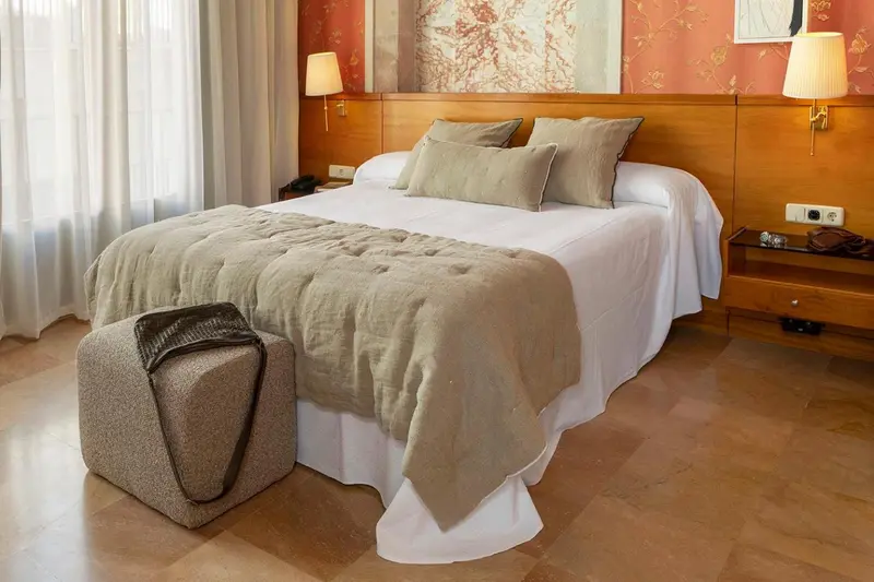 Une chambre lumineuse avec un grand lit recouvert d'une couette et de coussins.