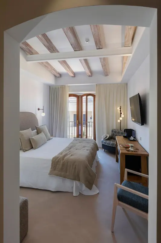 Une chambre lumineuse avec un lit fait et un bureau près d'une fenêtre.