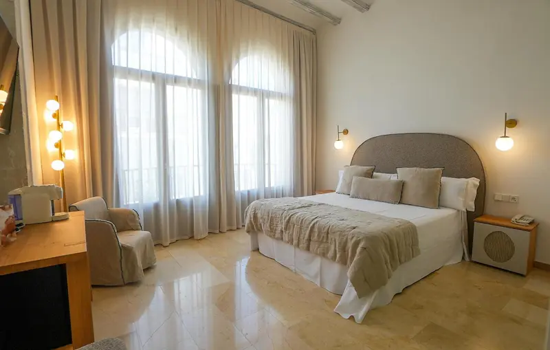 Une chambre lumineuse avec un grand lit et un coin salon.