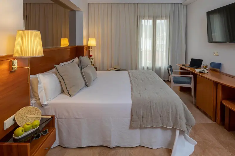 Une chambre lumineuse avec un grand lit et un bureau.