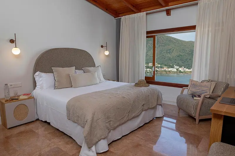 Chambre lumineuse avec un grand lit et vue sur la mer.