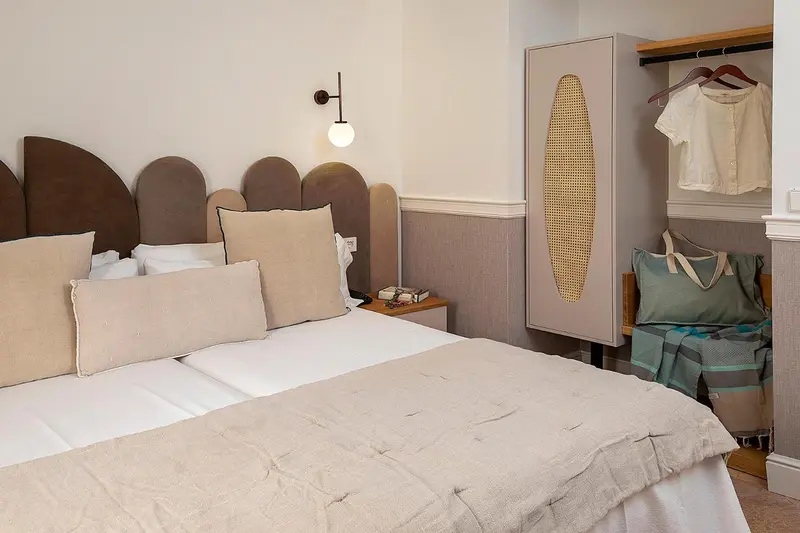 Une chambre lumineuse avec un grand lit et une tête de lit décorative.