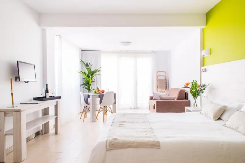 Une chambre lumineuse avec un lit, un coin repas et un espace détente.