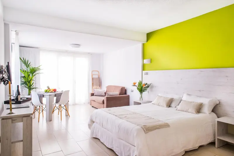 Une chambre lumineuse avec un lit double et un espace repas.