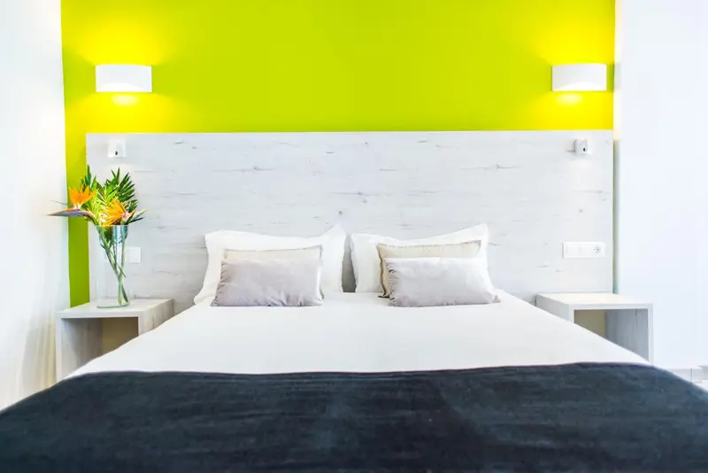 Une chambre lumineuse avec un grand lit et un mur vert vif.