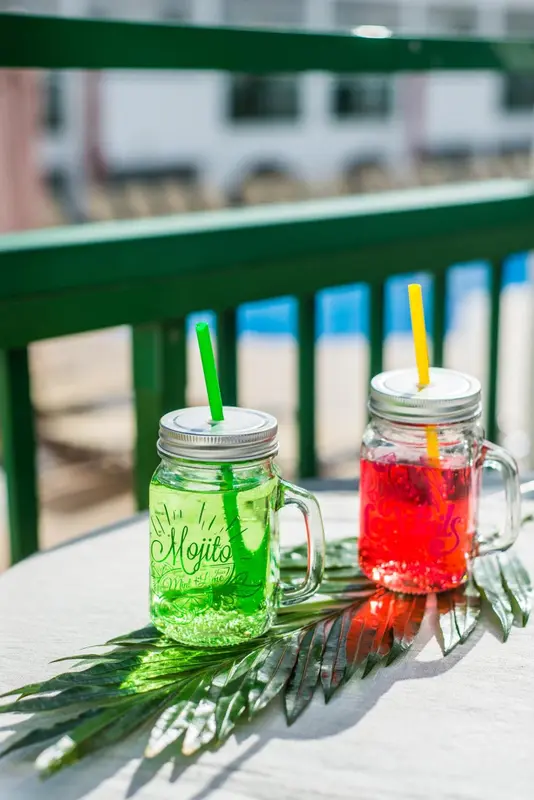 Deux cocktails colorés sur une table en extérieur.