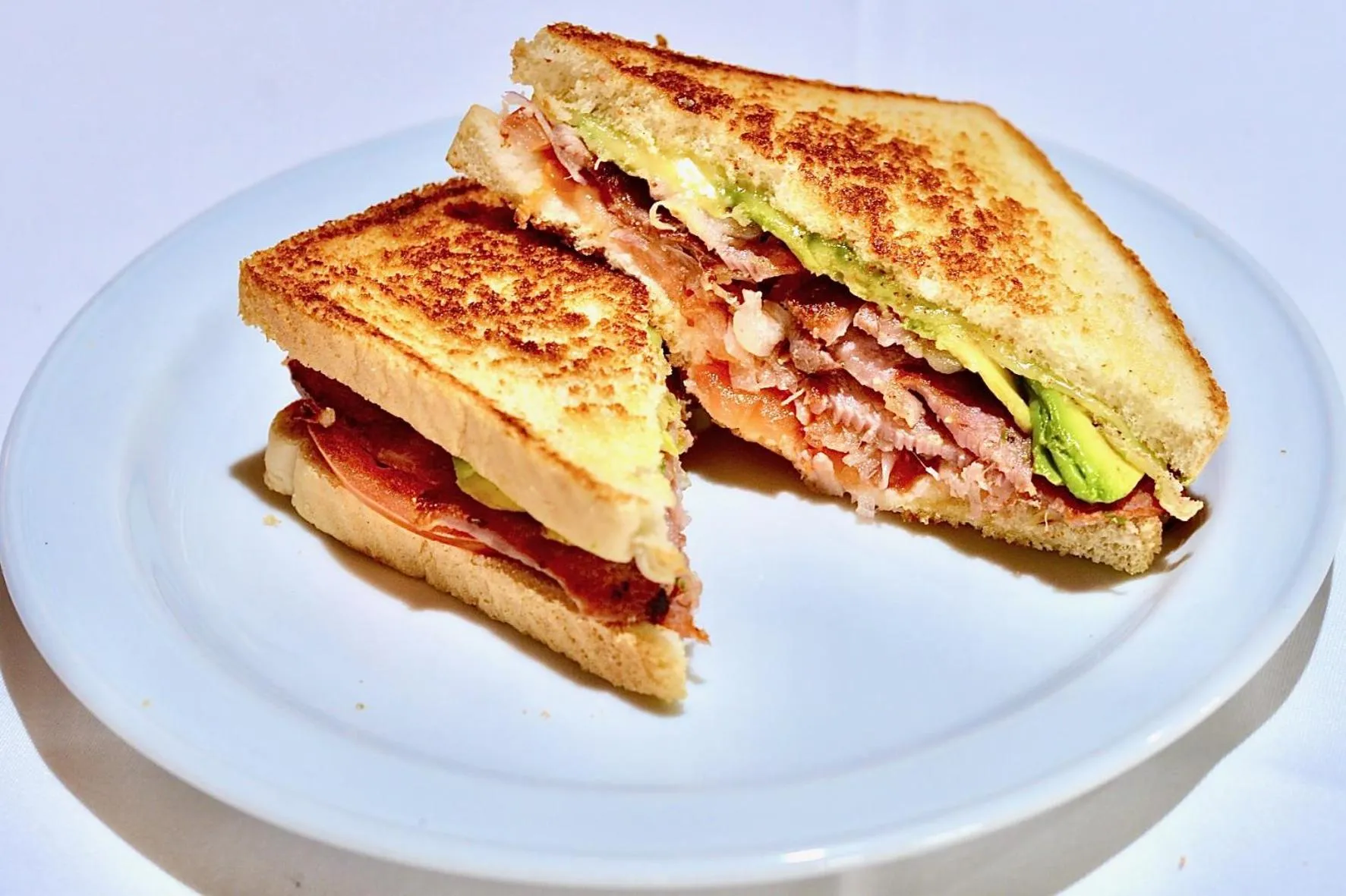 Deux sandwichs grillés coupés en triangle sont servis sur une assiette blanche.