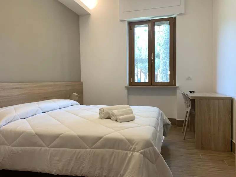 Une chambre lumineuse avec un lit double et un bureau.