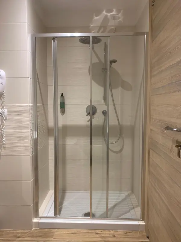Une douche à l'italienne avec parois vitrées et robinetterie chromée.