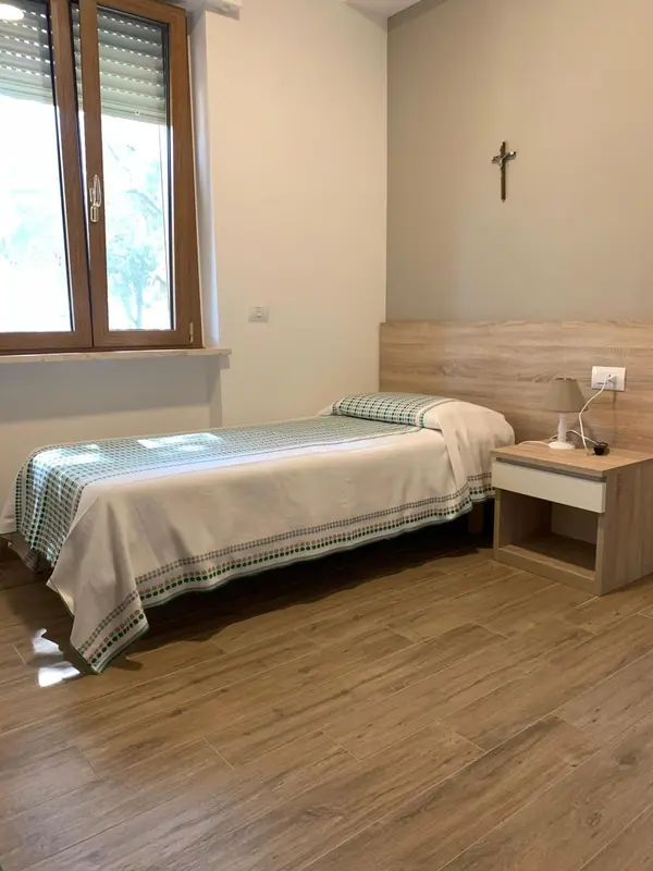 Une chambre simple avec un lit recouvert d'une courtepointe verte et une fenêtre.