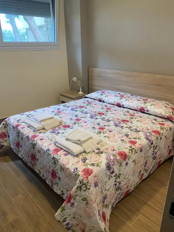 Une chambre lumineuse avec un grand lit recouvert d'une couette fleurie.