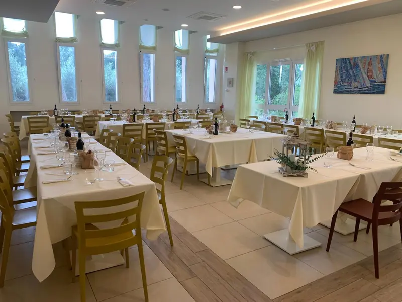 Une salle lumineuse avec des tables dressées pour un repas.