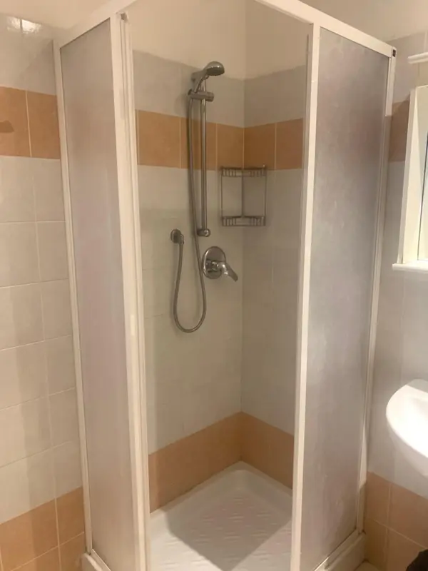 Douche cabinee avec pommeau et robinetterie chromees.