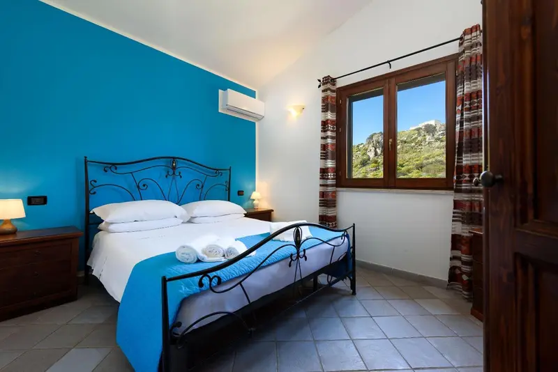 Une chambre lumineuse avec un lit double et une vue sur le paysage.