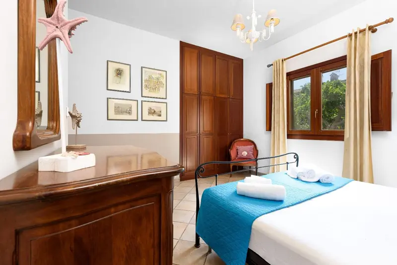 Une chambre lumineuse avec un lit fait et un meuble en bois.