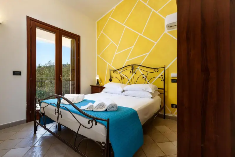 Une chambre lumineuse avec un lit double et un accès à une terrasse.