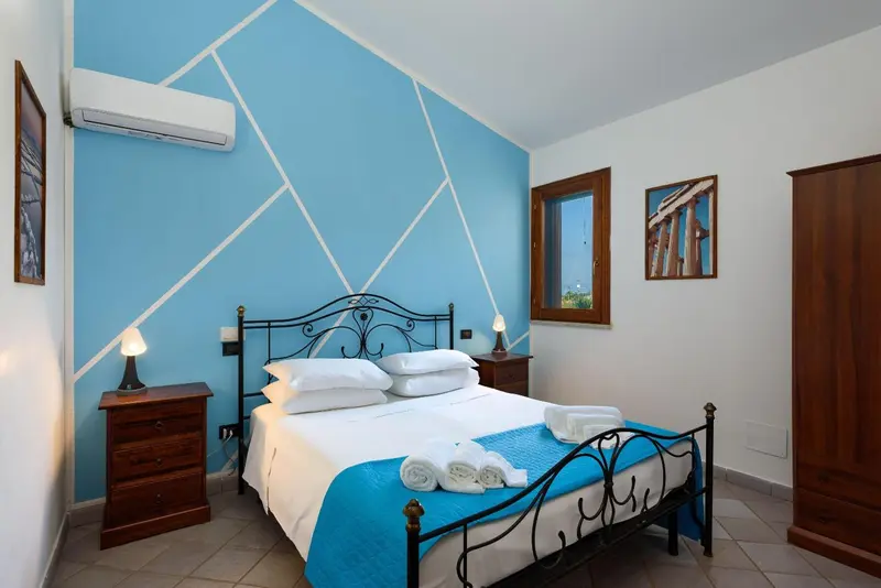 Une chambre lumineuse avec un lit double et une décoration murale géométrique.