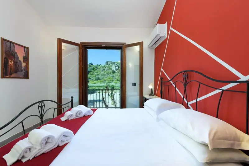 Une chambre lumineuse avec un lit fait et une vue sur la végétation.