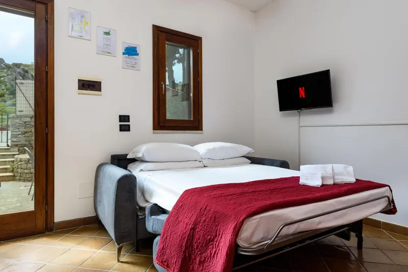 Une chambre avec un canapé-lit et une télévision murale.