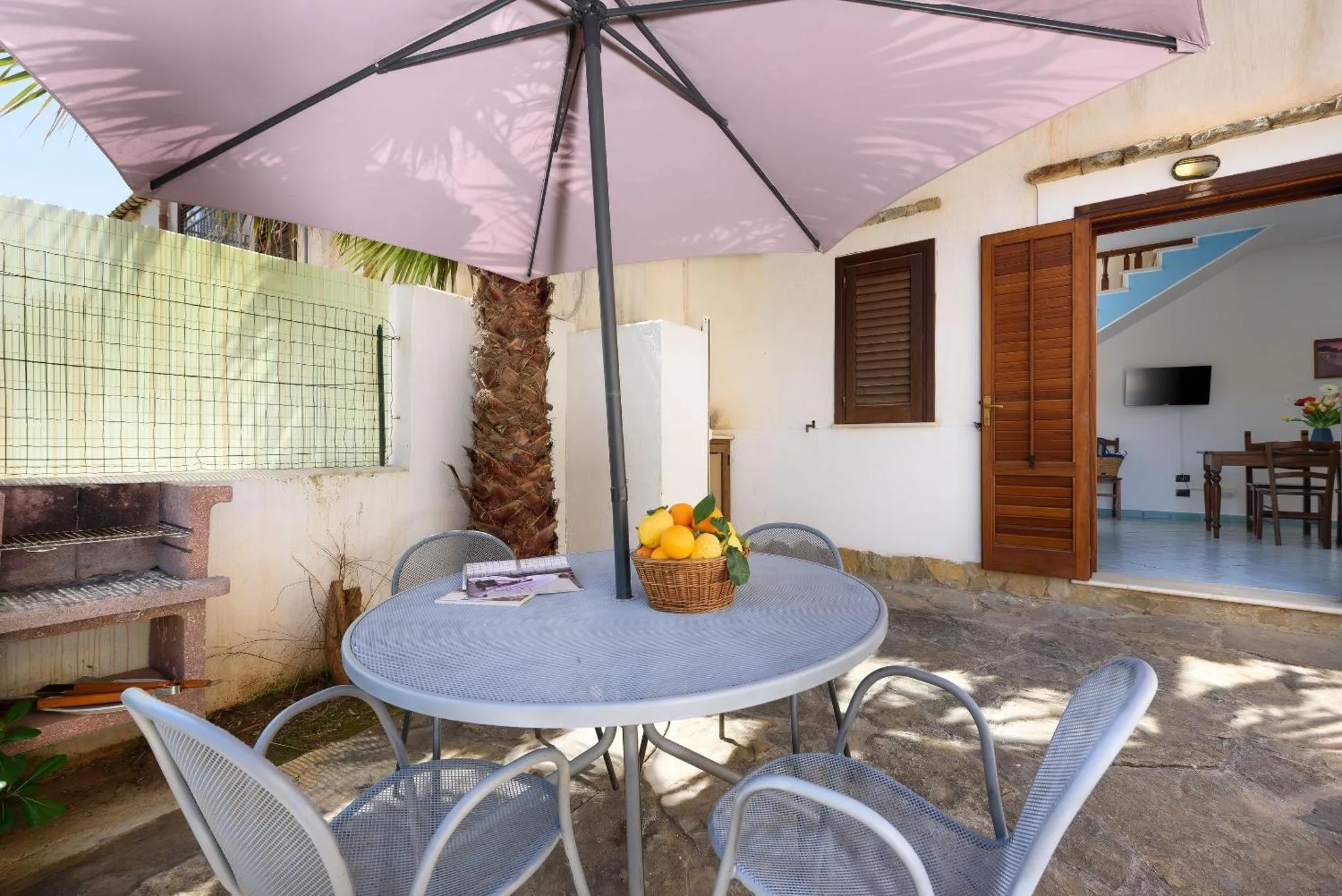 Une table ronde avec des chaises se trouve sur une terrasse ombragée.