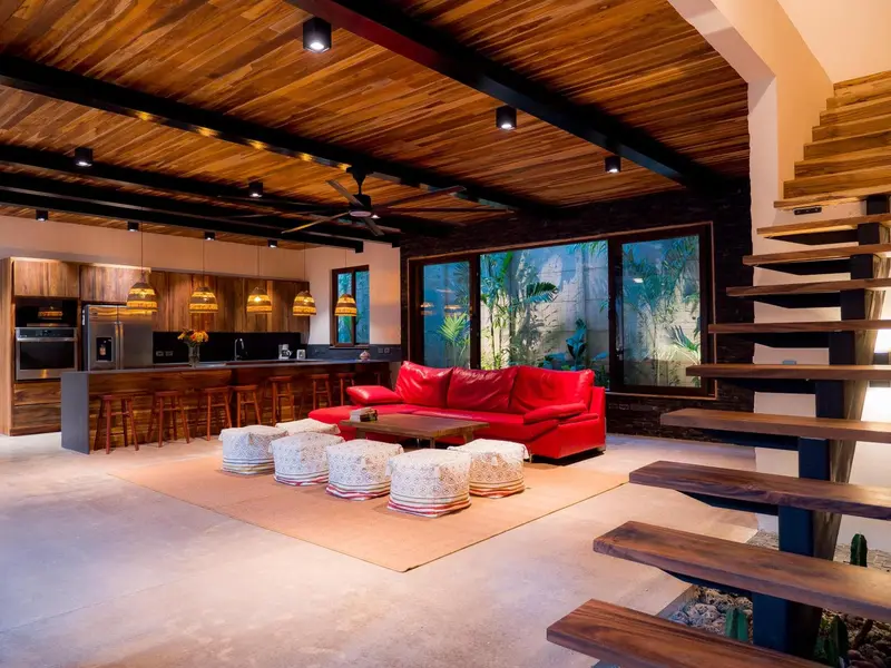 Un espace de vie intérieur moderne avec un canapé rouge et une cuisine ouverte.