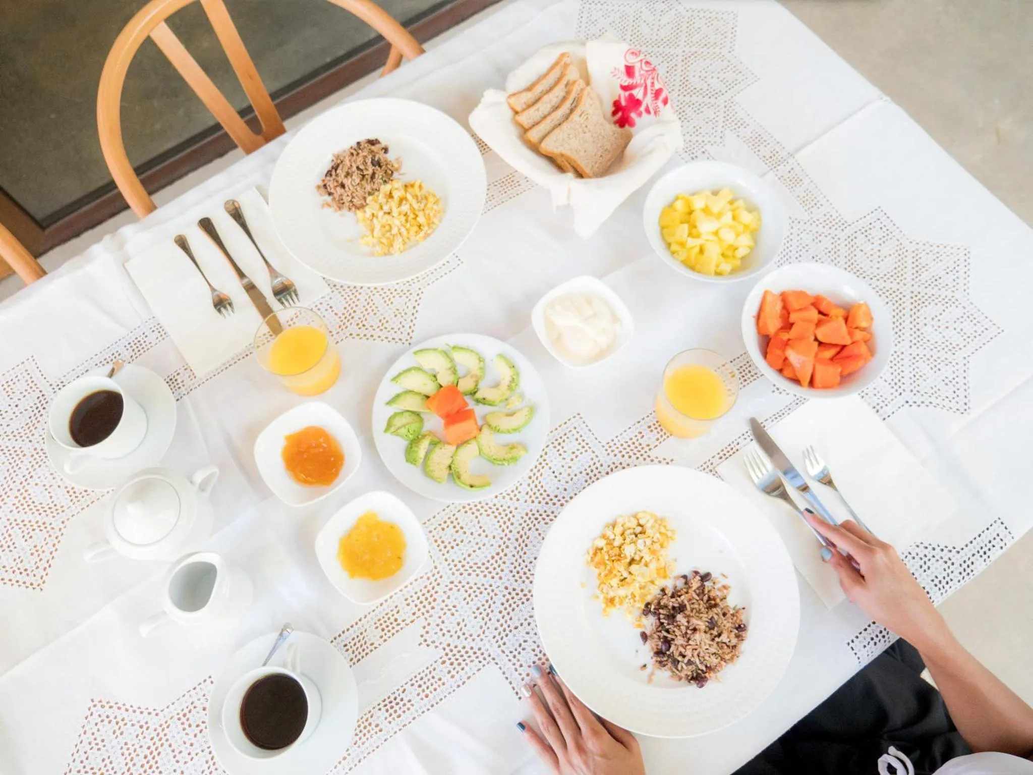 Une table blanche est dressée pour un petit-déjeuner copieux avec des fruits, des céréales et des œufs.