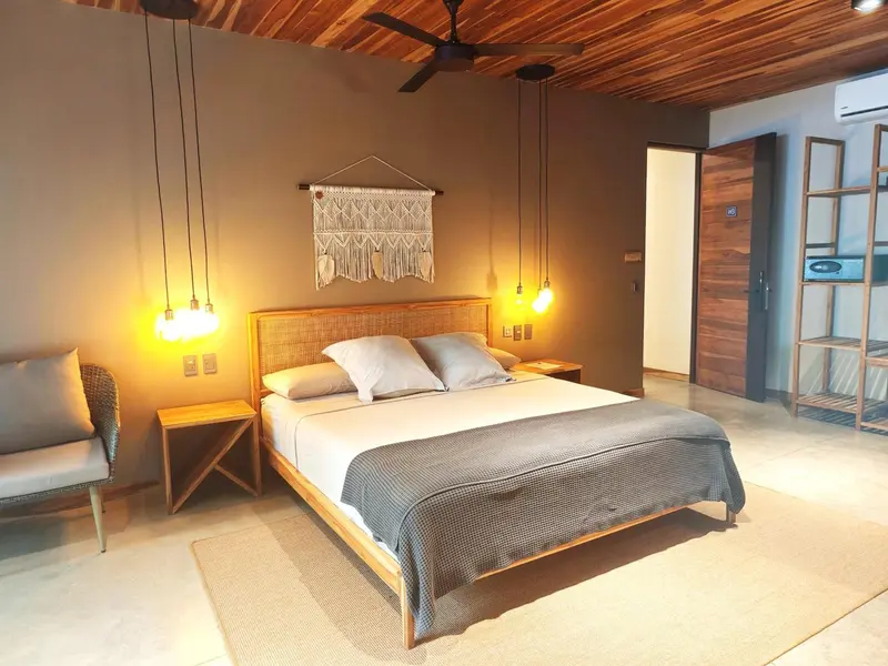 Une chambre lumineuse avec un grand lit et une décoration en macramé.