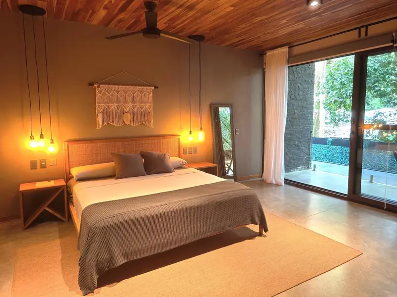 Une chambre lumineuse avec un grand lit et un accès à une terrasse.
