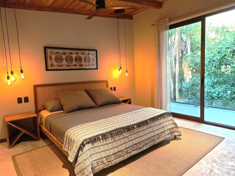 Une chambre lumineuse avec un grand lit et un accès à une terrasse.