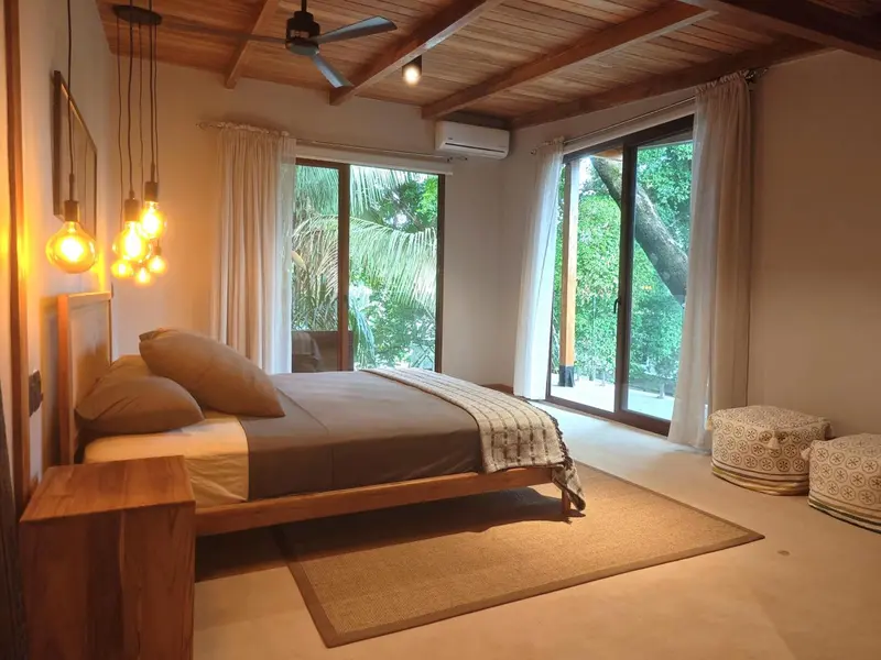 Une chambre lumineuse avec un lit fait et une vue sur la végétation.