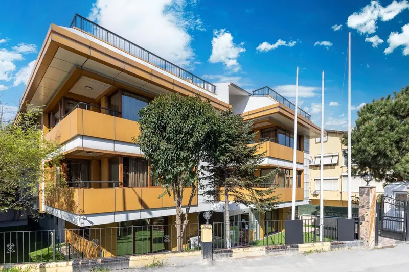 Bâtiment moderne aux façades colorées avec des balcons et une végétation luxuriante.