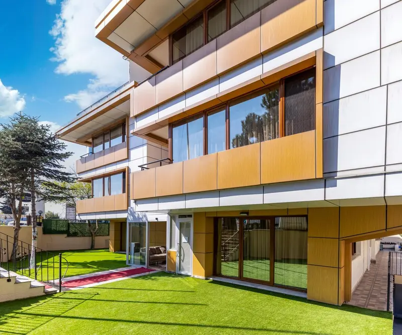 Facade moderne d'un bâtiment avec des balcons et une pelouse verte.