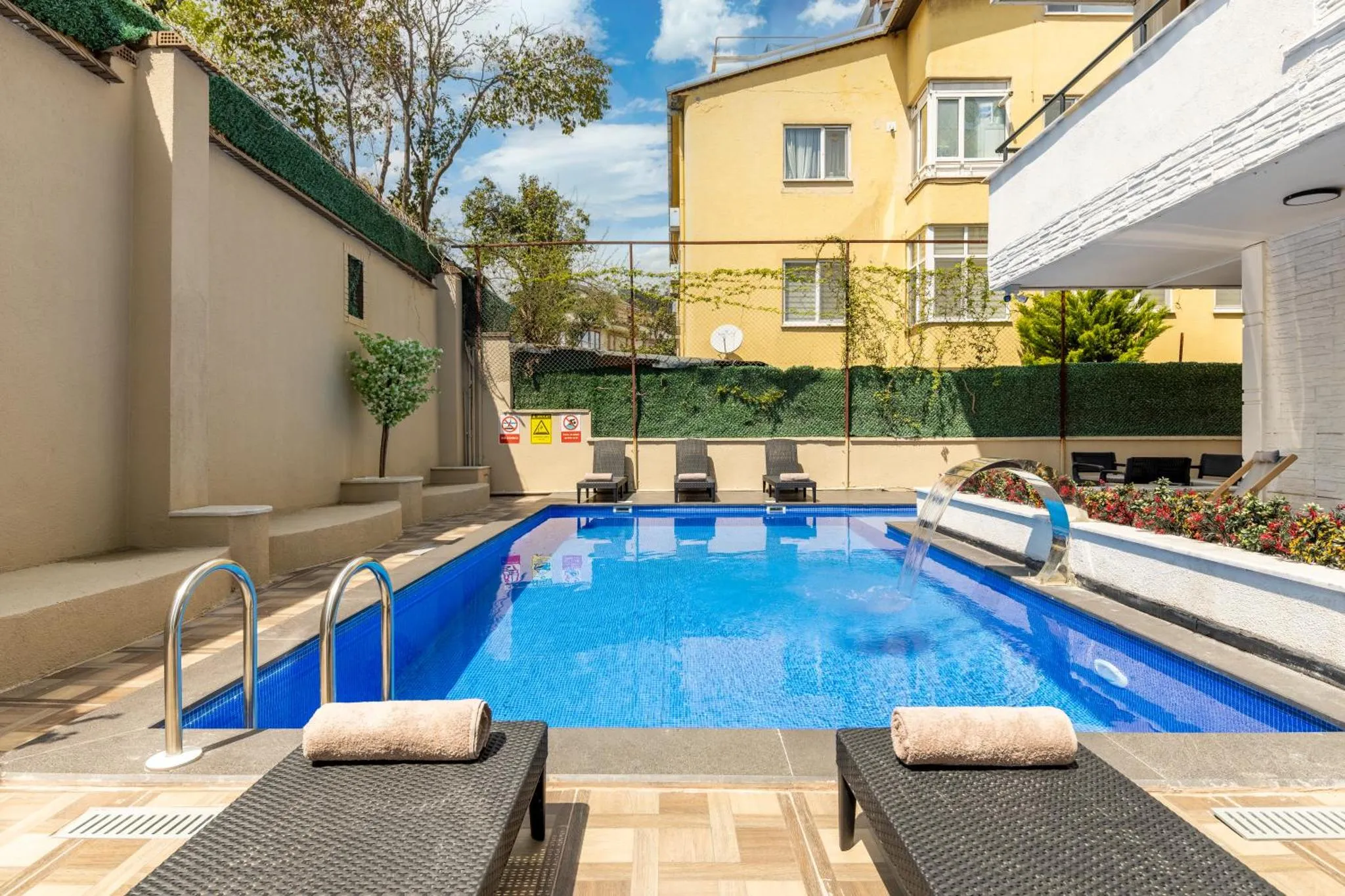 Une piscine rectangulaire avec des transats et une végétation luxuriante.