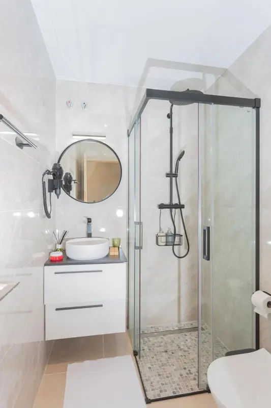 Une salle de bain moderne avec une douche à l'italienne et un miroir rond.