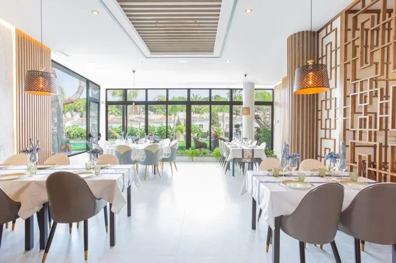 Une salle lumineuse avec des tables dressées pour un repas.
