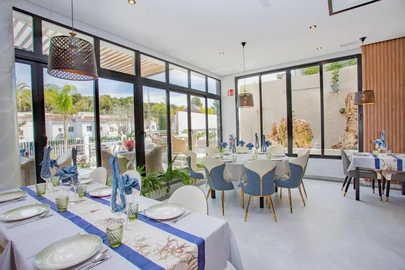 Une salle lumineuse avec des tables dressées pour un repas.