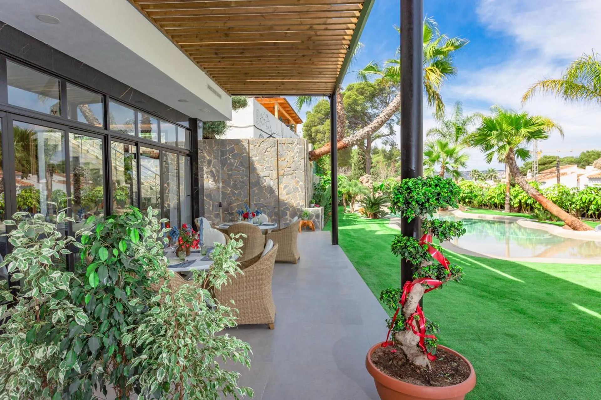 Terrasse ombragée avec mobilier de jardin et végétation luxuriante.