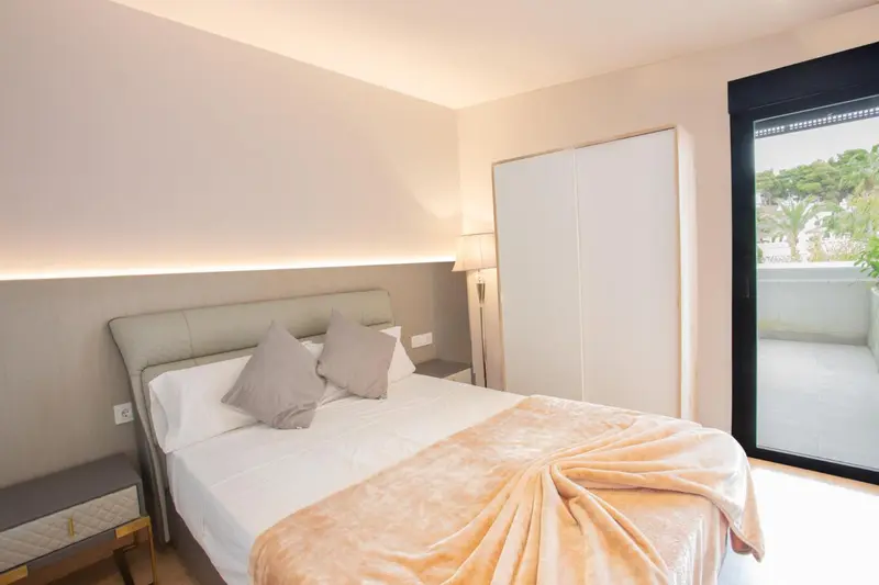 Une chambre lumineuse avec un grand lit et un accès à une terrasse.
