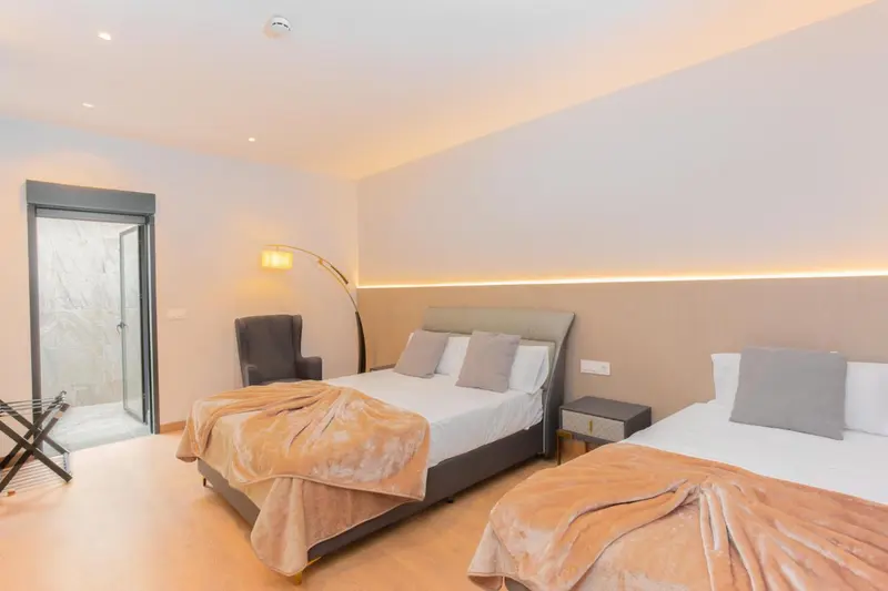 Une chambre lumineuse avec deux lits et un fauteuil.