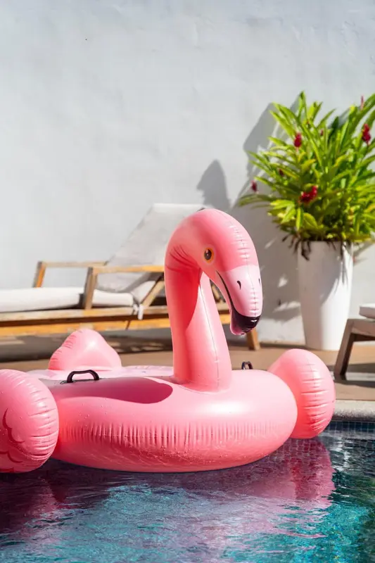 Flamant rose gonflable flottant dans une piscine ensoleillée.