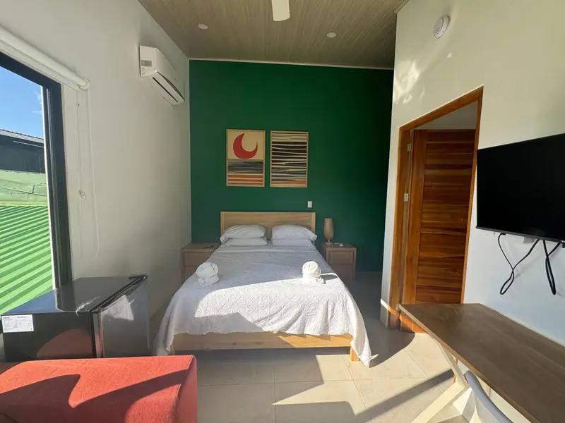 Une chambre lumineuse avec un grand lit recouvert d'une courtepointe blanche.