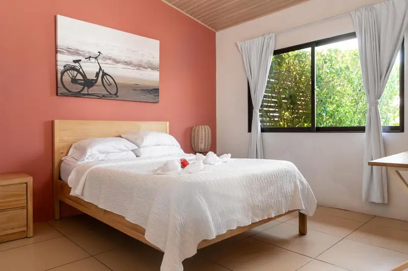 Une chambre lumineuse avec un grand lit recouvert de draps blancs et des oreillers.