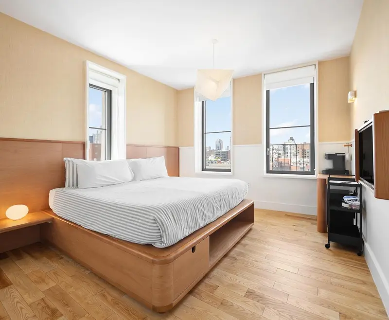 Une chambre lumineuse avec un grand lit et deux fenêtres.