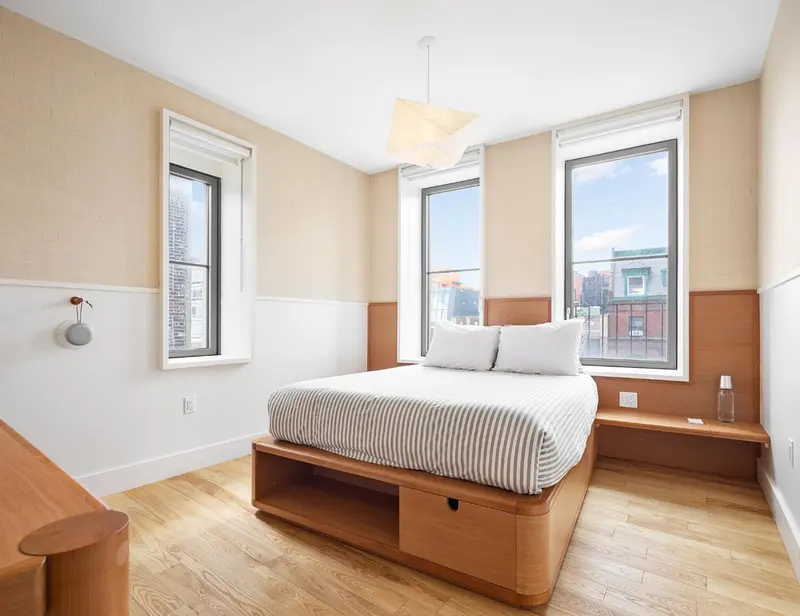 Une chambre lumineuse avec un grand lit et deux fenêtres.