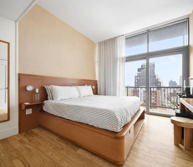Une chambre lumineuse avec un grand lit et une vue sur la ville.